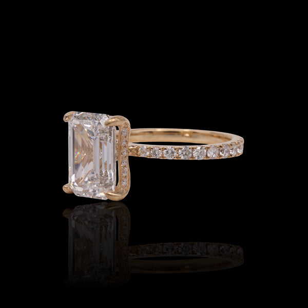 Gold ring with a large rectangular diamond and smaller diamonds on the band against a black background