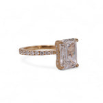 Rose gold ring with a large diamond and smaller diamonds on the band against a white background