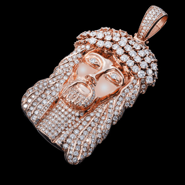 Rose gold diamond-encrusted Jesus face pendant laid on a black background