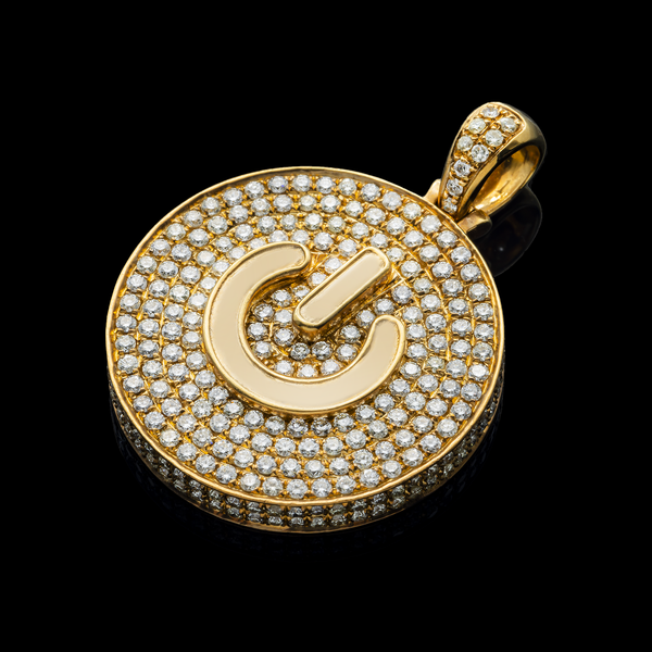 Gold pendant power play button with diamond accents on a black background
